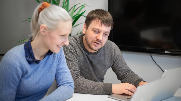 Två personer som använder ett e-postmarknadsföringsverktyg på bärbar dator