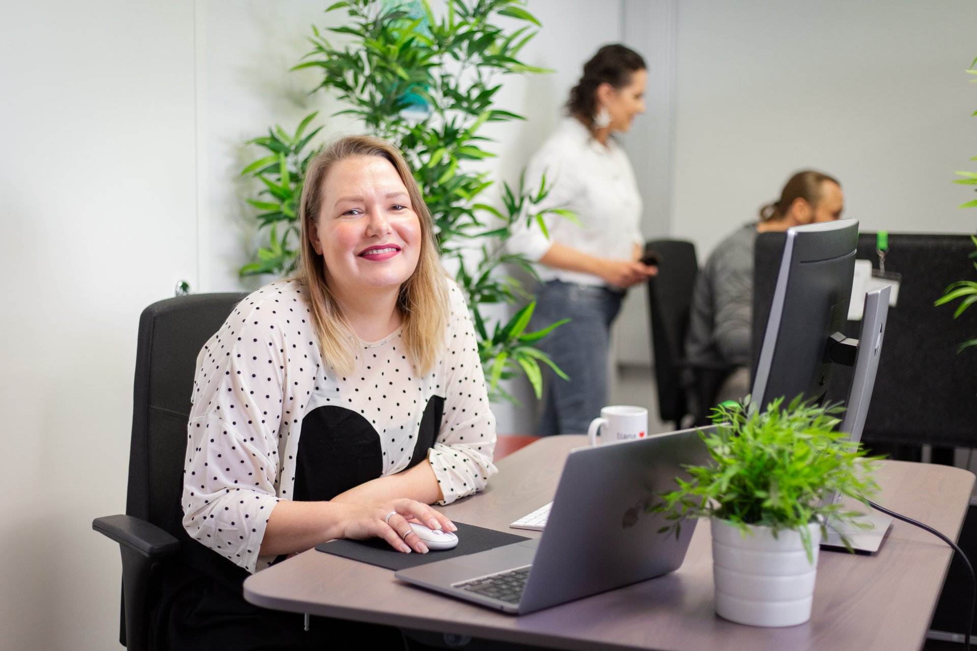 A smiling person using newsletter tool LianaMailer on laptop