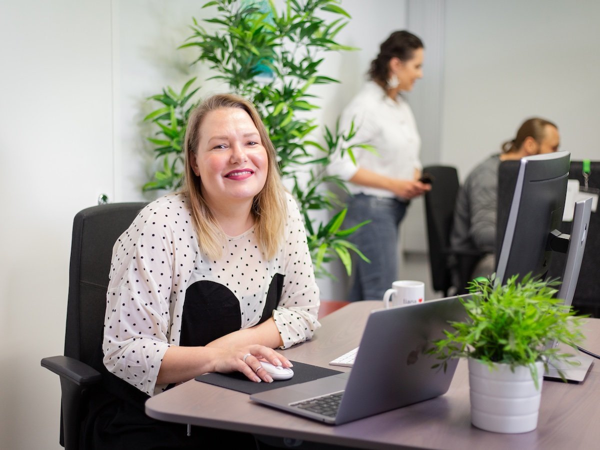 A smiling person using newsletter tool LianaMailer on laptop