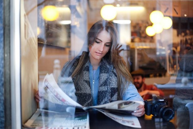 Kvinna läser tidning på restaurang